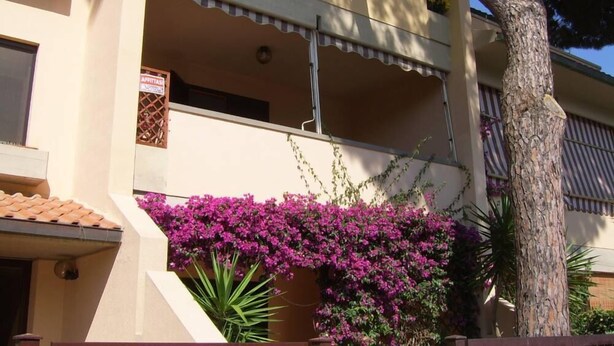 A building with a balcony, a sign indicating a price, and a tree. - Apartment/ flat - Marina di grosseto (Marina di Grosseto)