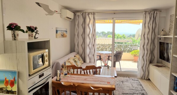 A cozy living room with a dining table, sofa, and a view of the outdoors.