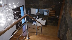 Un interior moderno con una escalera de madera, una lámpara decorativa y una pared de piedra.
