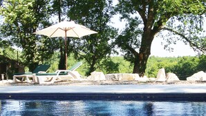 Une piscine avec des chaises longues et un parasol.