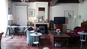 Un salon chaleureux avec une cheminée, un téléviseur et un coin repas comprenant une table et des chaises.