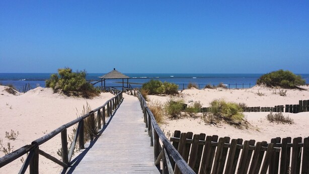 A wooden boardwalk leading to a beach with a small structure at the end. - Chipiona Corner semi-detached house on the beachfront (Chipiona)