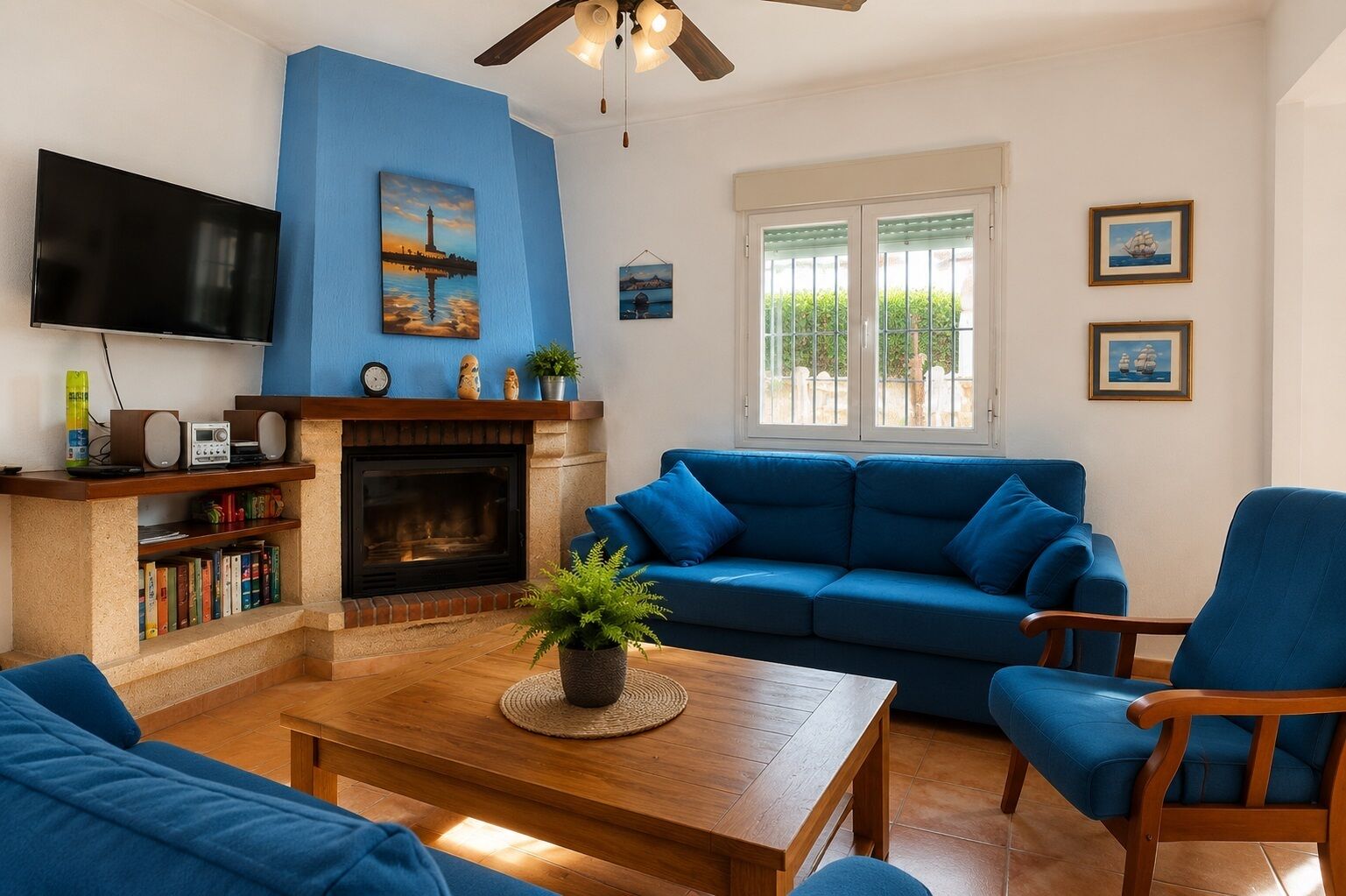 Een woonkamer met een blauwe bank, een houten salontafel, een open haard en een televisie.