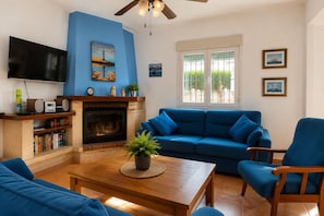 A living room with a blue sofa, a wooden coffee table, a fireplace, and a television.