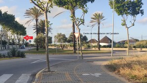 A street view with palm trees, a pedestrian crossing, and a sign indicating a 30m distance. - Chipiona Corner semi-detached house on the beachfront (Chipiona)