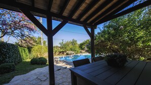 A covered patio with a stone floor, a pool, and a table with chairs. - Beautiful villa for 4 people with private pool   (Urval)