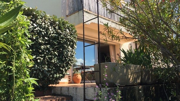 A courtyard with a wooden pergola, potted plants, and a view of a building with a balcony. - Spacious 8-Bed Villa; Pool, Mountain Views, Easy Access to Céret, Coast & Spain (Céret)