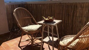 A balcony with wicker chairs and a small table, a bowl of fruit, and a view of distant mountains. - Spacious 8-Bed Villa; Pool, Mountain Views, Easy Access to Céret, Coast & Spain (Céret)