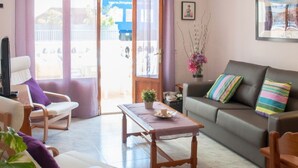 Una sala de estar con un sofá, sillones, una mesa de centro y un televisor.