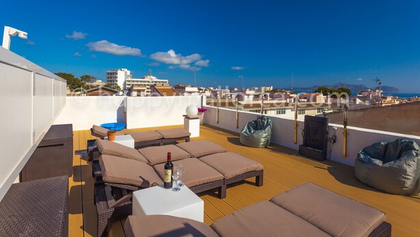 Terraza en la azotea con sillones, una mesa y vistas a la ciudad.