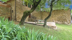 A stone building with a rustic exterior, a wooden bench, and a picnic table in a garden area. - Ancient with private garden and swimming pool, characteristic and rustic style. Situated in the gree (Arezzo)