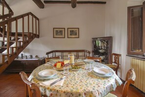 A dining area with a wooden staircase, a table set for two with plates, glasses, and a pitcher.