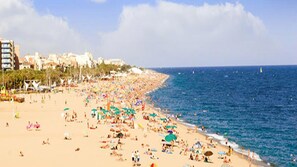 Une plage bondée, avec de nombreux parasols et des gens qui profitent de la mer.