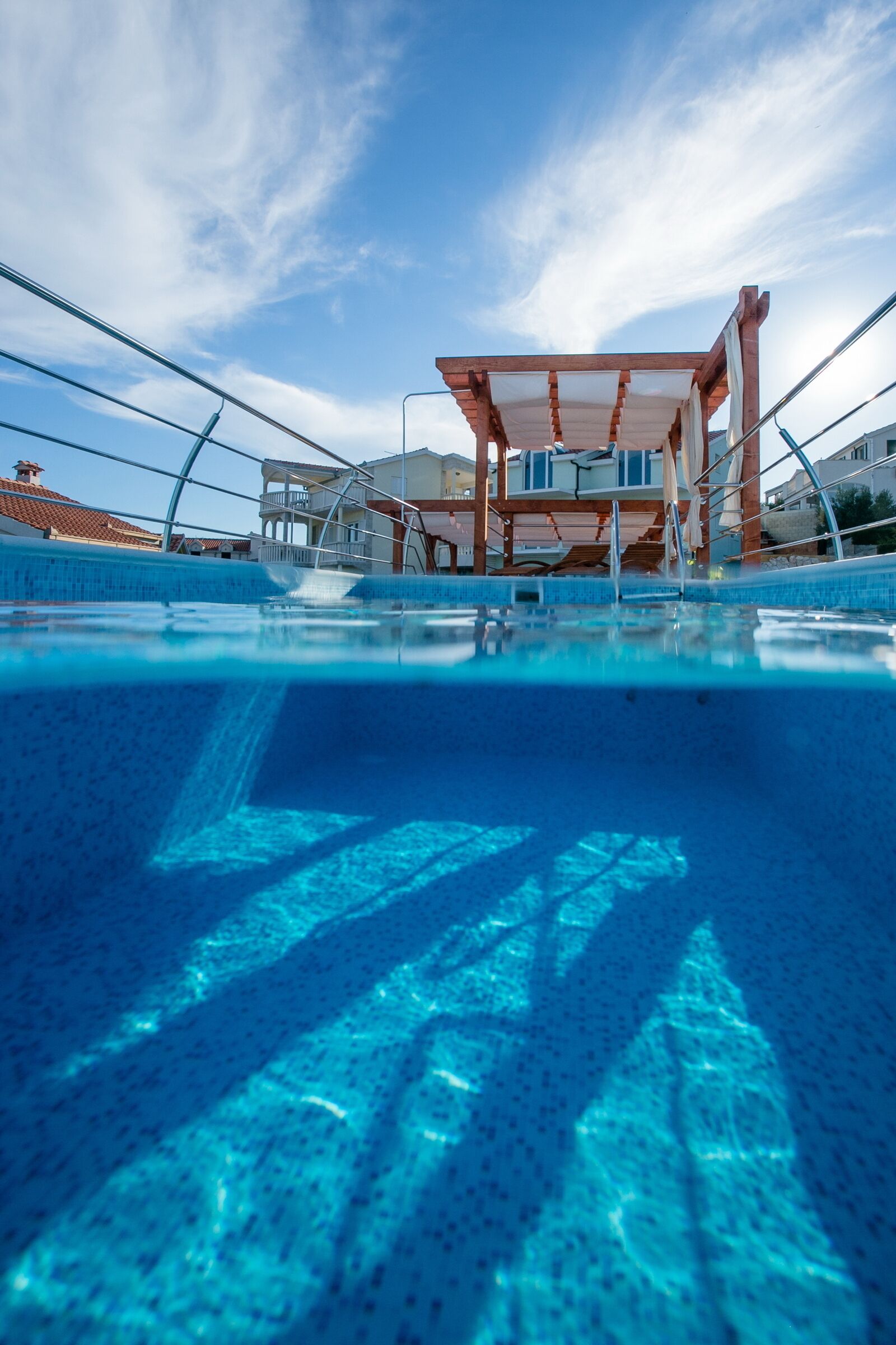 A clear view of a swimming pool with a wooden deck and a covered seating area.