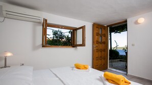 Une chambre d’hôtel avec un lit, une fenêtre donnant sur l’extérieur, une porte menant à l’extérieur et un climatiseur fixé au mur.