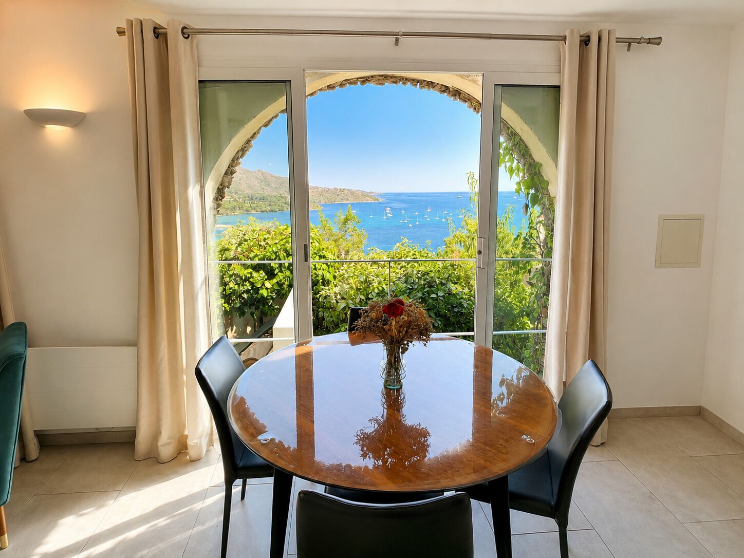 Ein Essbereich mit einem runden Tisch, Stühlen und Meerblick durch große Fenster.