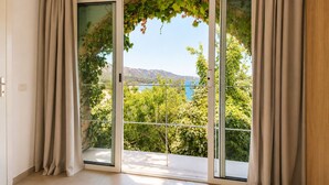 A room with a sliding glass door leading to a balcony with a view of a lake and mountains. - apartment/ flat - 2 rooms - 4/5 persons (Saint-Florent)