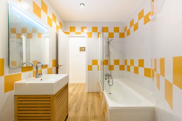 Une salle de bain avec un lavabo, un miroir et une baignoire.