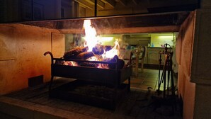 Une grille métallique dans laquelle brûle un feu, le tout étant entouré d’une structure en béton.