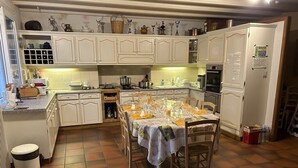 Une cuisine avec des meubles blancs, une table à manger dressée pour quatre personnes et un sol carrelé.