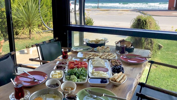 A table set with various foods and drinks, overlooking a beach and ocean view. - 8 Rooms Hotel (Gallipoli)