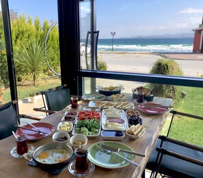 Een tafel gedekt met diverse gerechten en drankjes, met uitzicht op een strand en zee.