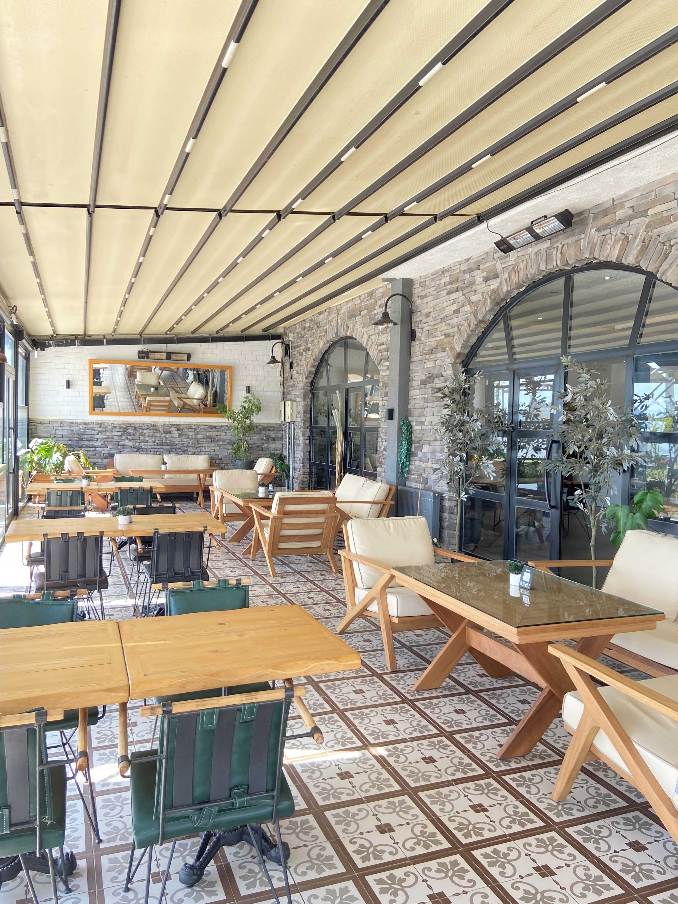 A cafe with outdoor seating, stone walls, and a tiled floor.