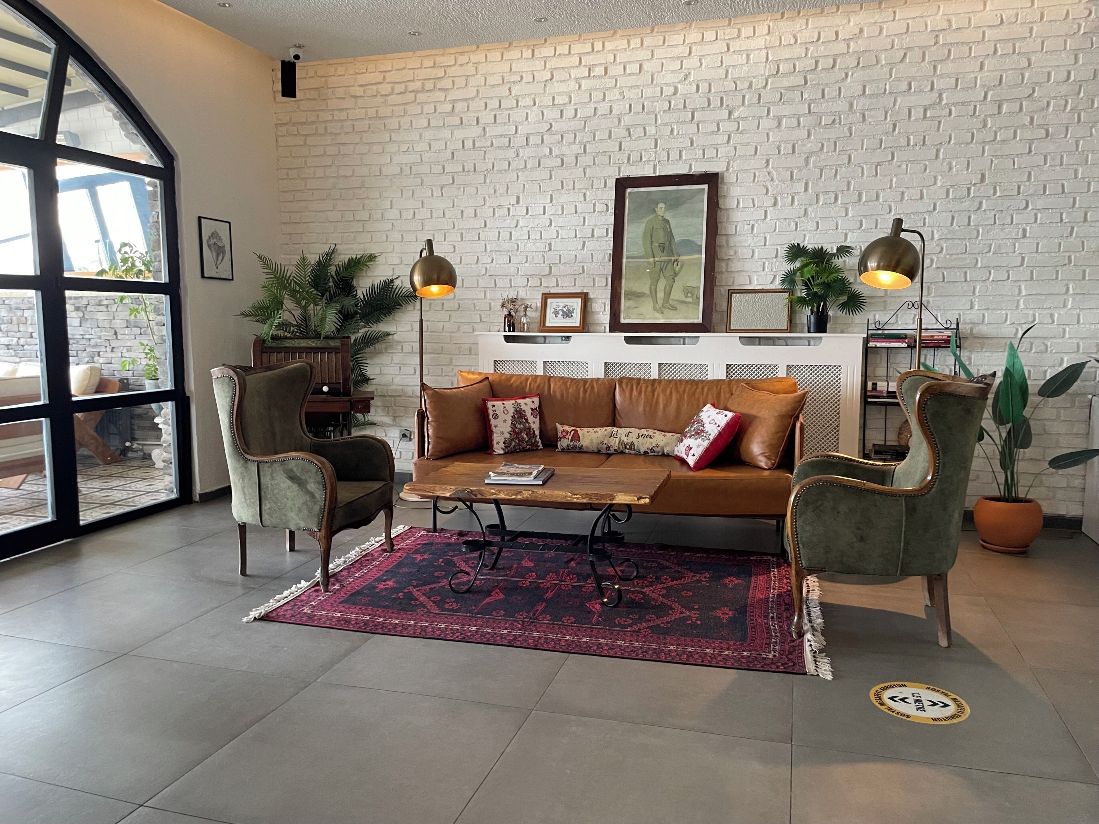 Una sala de estar con sofá, sillones, una mesa de centro, alfombra estampada y pared de ladrillo.