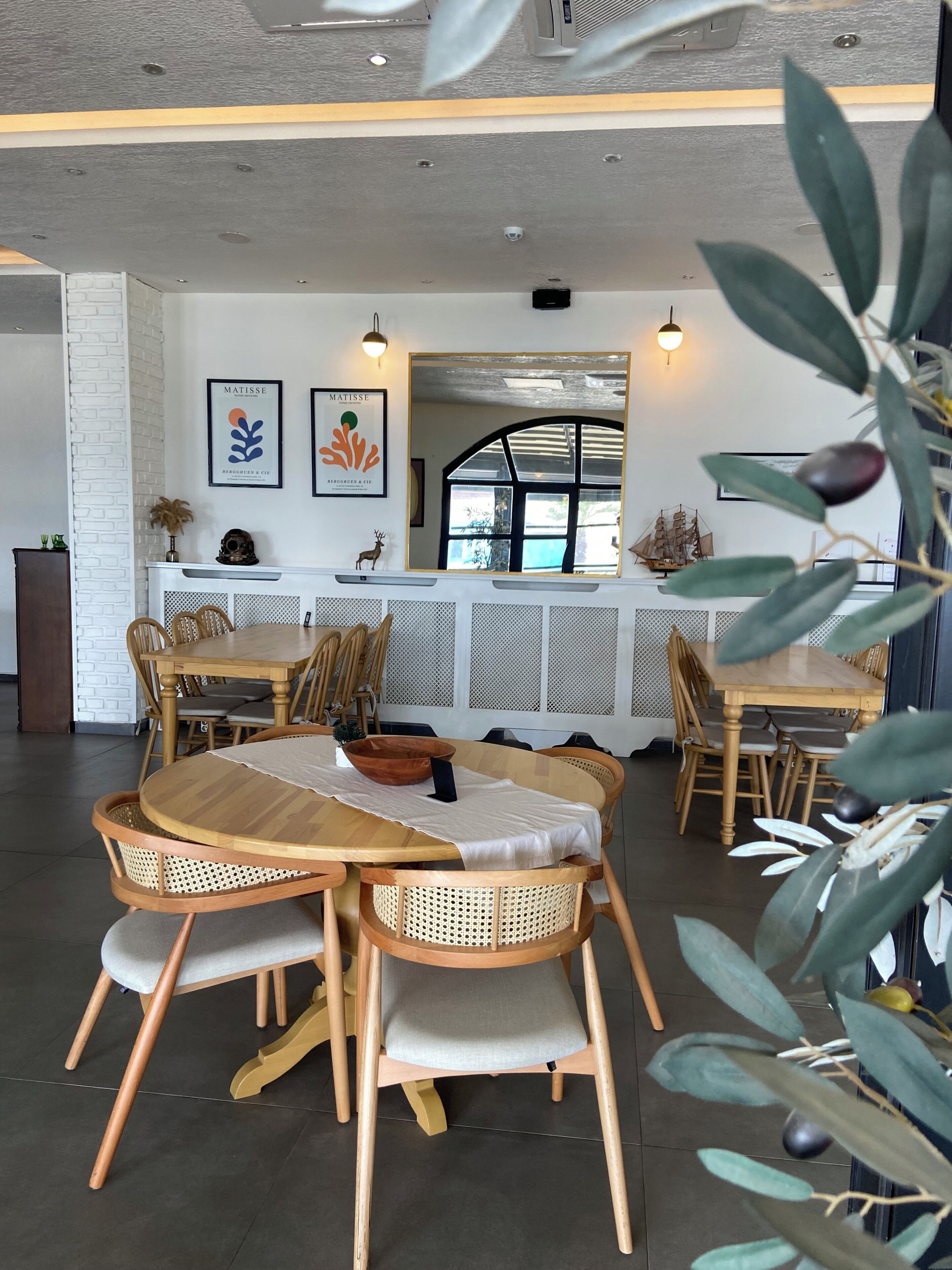 Uma sala de jantar com uma mesa e cadeiras de madeira, uma parede branca com obras de arte e uma janela com vista.