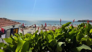 A beach view with a clear sky, a tiled roof structure, and lush green plants in the foreground. - 8 Rooms Hotel (Gallipoli)