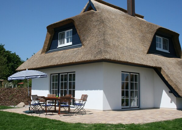 A house with a thatched roof, large windows, and a patio with outdoor furniture. - Family-friendly house under Ried, for 6 adults and 1 child, dogs allowed (Zinnowitz)