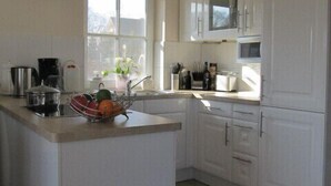 Una cocina moderna con armarios blancos, una isla central y un ventanal que proporciona luz natural.