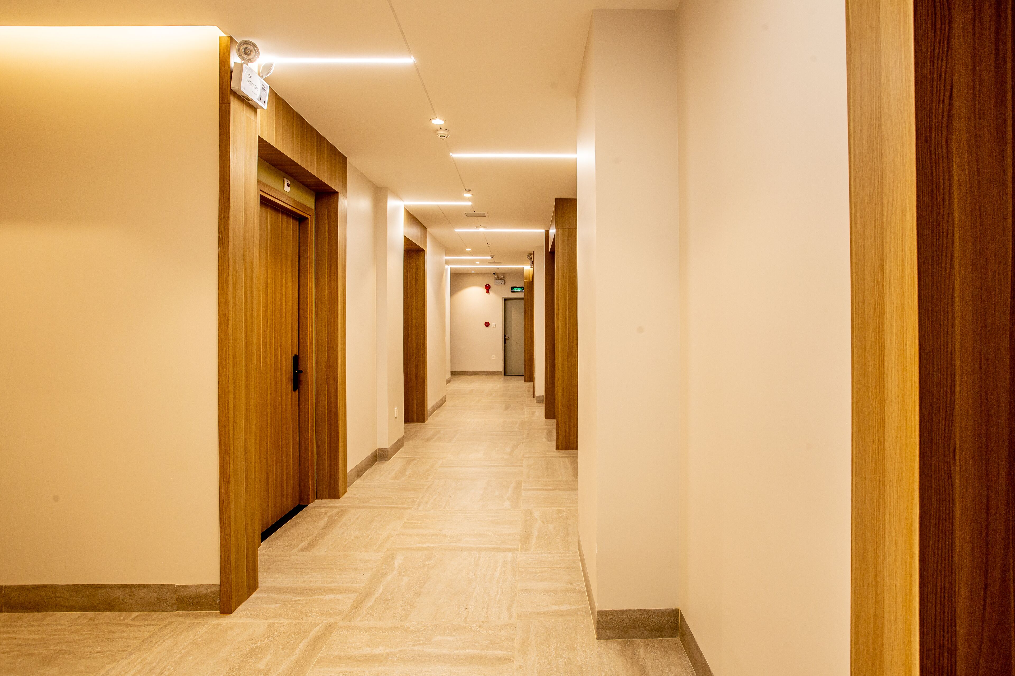 A hotel hallway with wooden doors and a tiled floor.