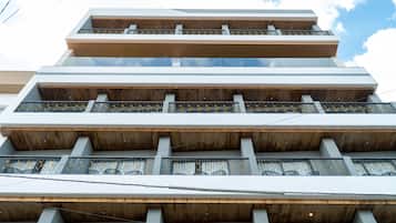 A multi-story building with a modern architectural design, featuring balconies with metal railings and wooden paneling.