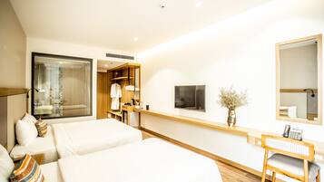 A hotel room with two beds, a desk, a mirror, and a TV.