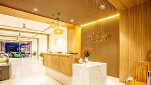 Un hall d’hôtel avec un comptoir de réception en marbre, des panneaux muraux en bois et une enseigne indiquant « Shangri-La ».