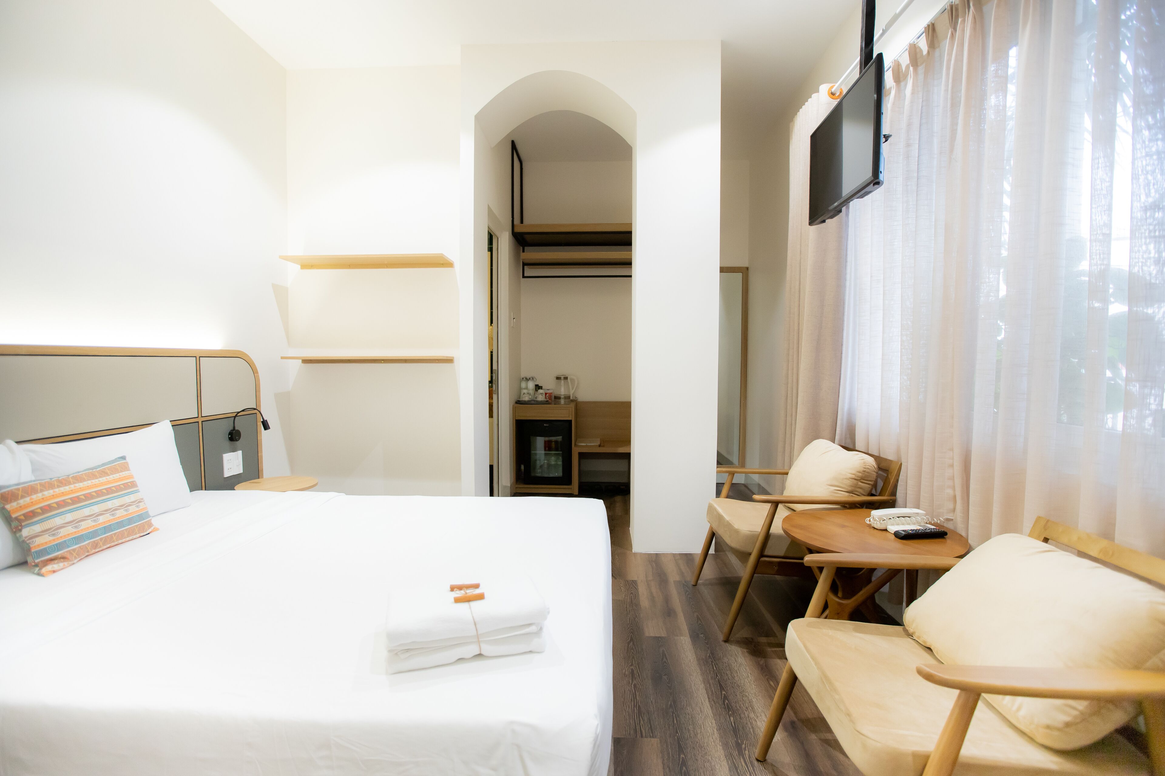 Una habitación de hotel con una cama, un escritorio, una silla y un televisor.