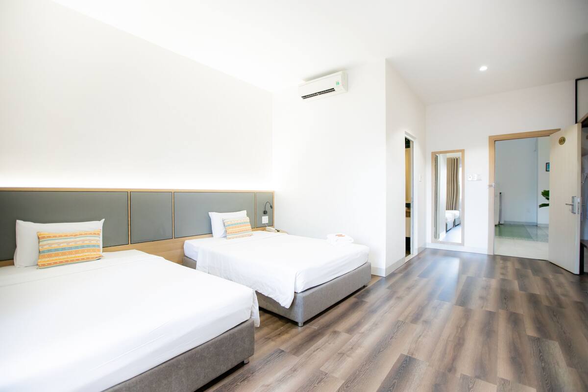 A hotel room with two beds, a modern design, and a wooden floor.