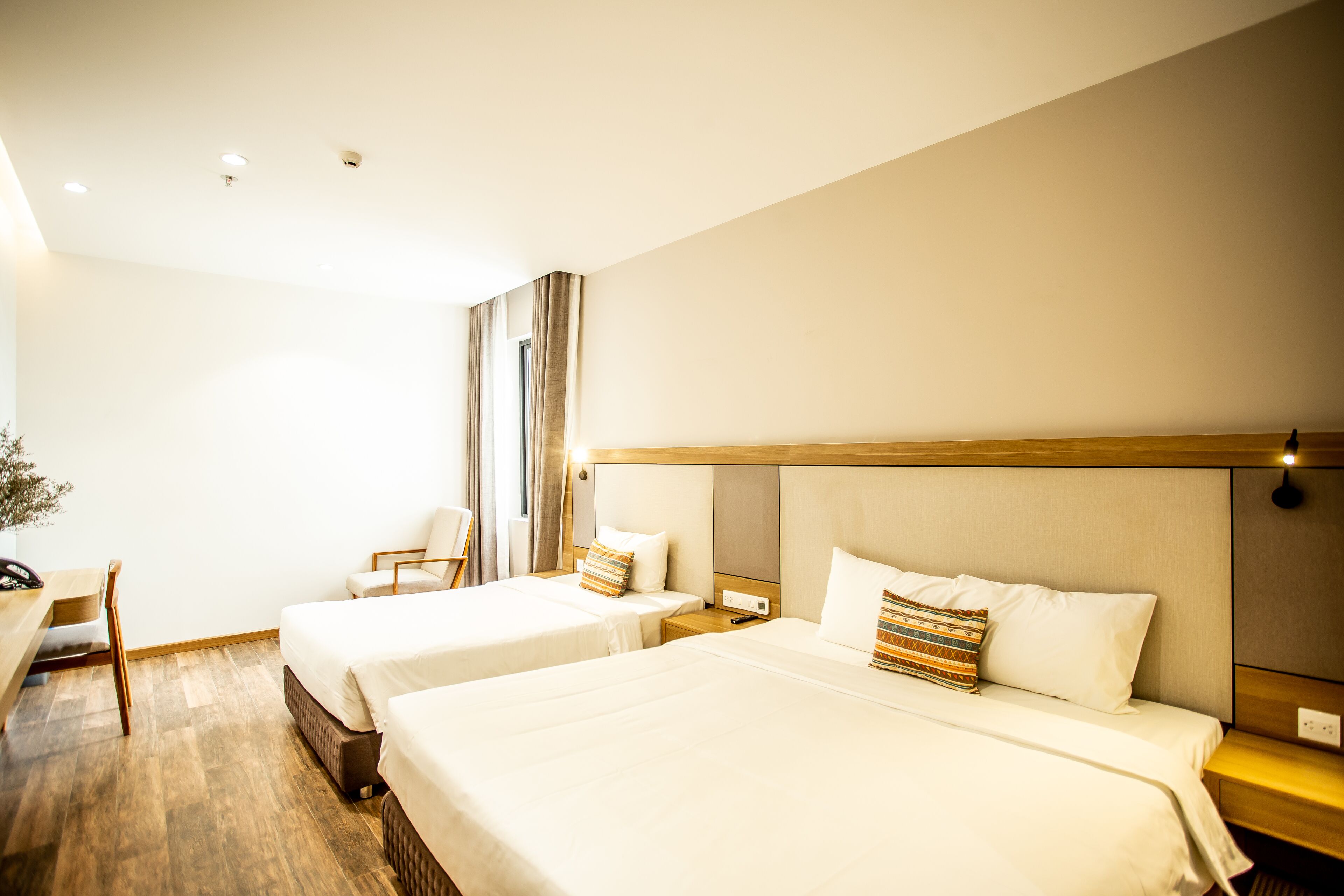 A hotel room with two beds, a desk, and a chair.
