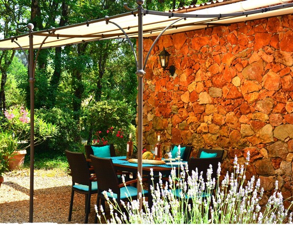 An outdoor patio with a stone wall, wicker furniture, and a pergola.