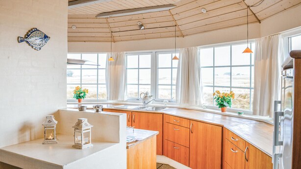 A kitchen with wooden cabinets, a white countertop, and a large window with curtains. - Nice home in Harboøre with kitchen (Harboøre)