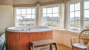 A bathroom with a freestanding bathtub, large windows, and a wicker chair. - Nice home in Harboøre with kitchen (Harboøre)