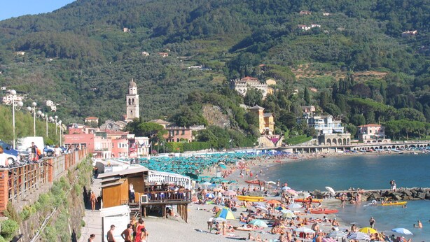 A beach with a view of a hill and a tower.