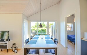 Cozy living space with a large dining table for six, a TV, and a seating area leading to an outdoor garden.
