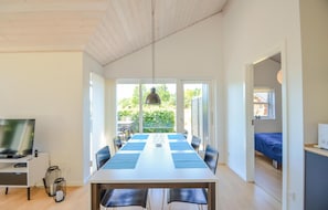 Cozy living space with a large dining table for six, a TV, and a seating area leading to an outdoor garden.