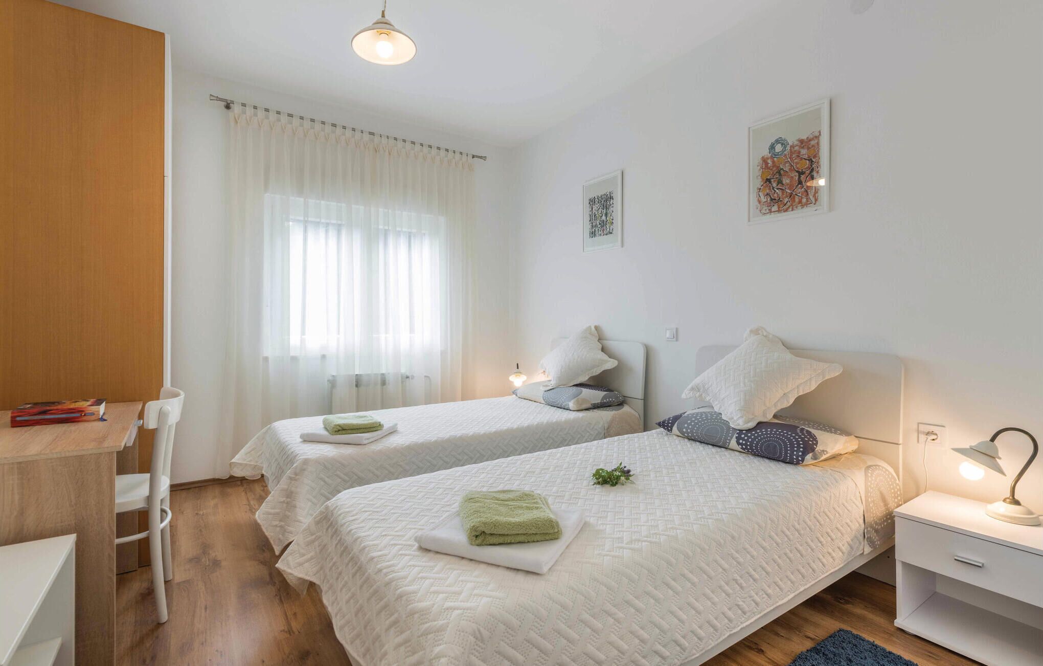 Un dormitorio limpio y moderno con dos camas, un escritorio y una silla.