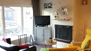 Una sala de estar con sofá, un sillón amarillo, chimenea y televisor.