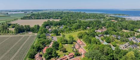An aerial view of a residential area with houses, green fields, and a marina with boats.