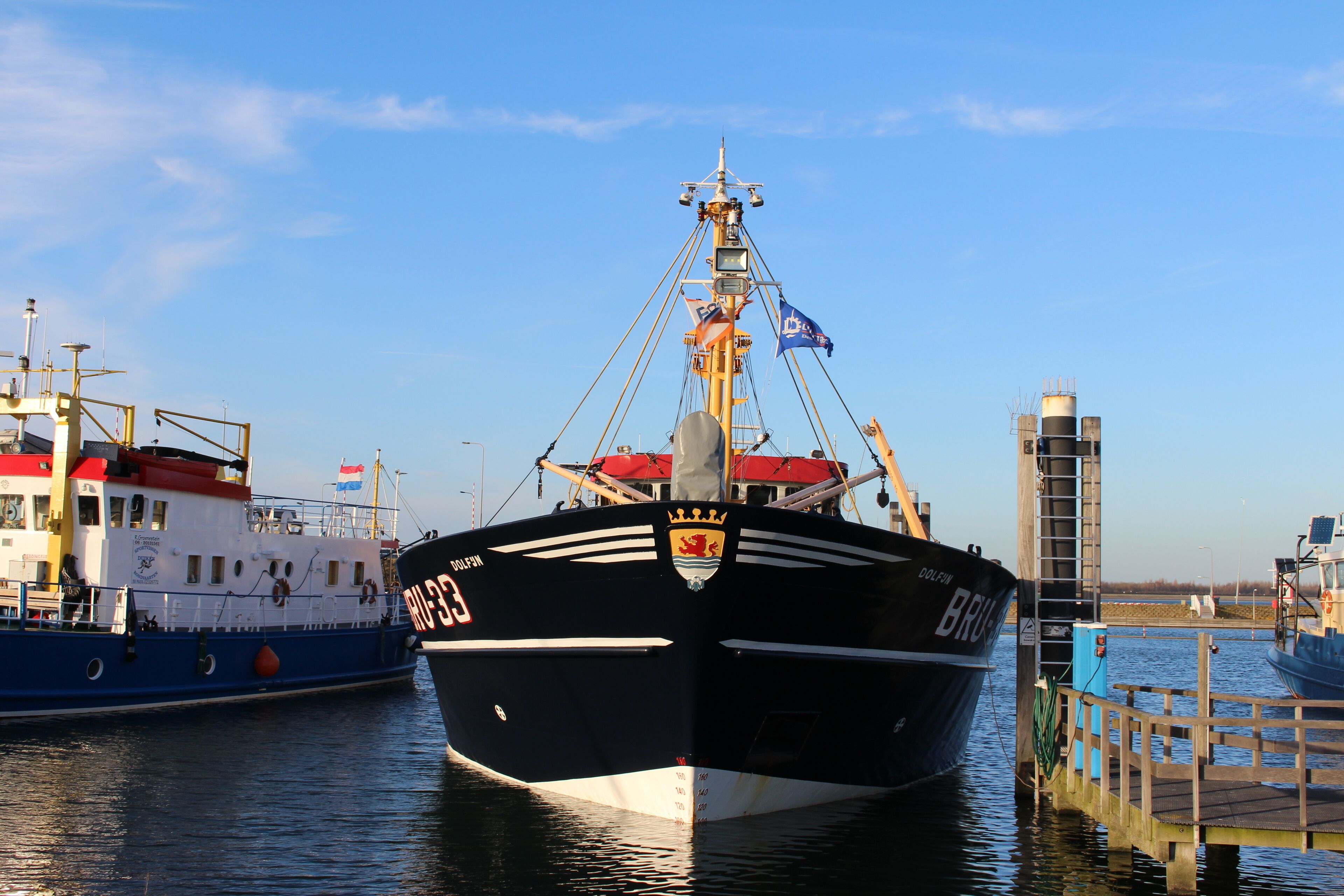 A large ship docked at a pier with a clear sky.