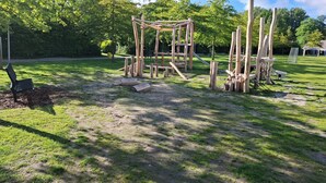 Un parque infantil con estructuras de madera y un banco.